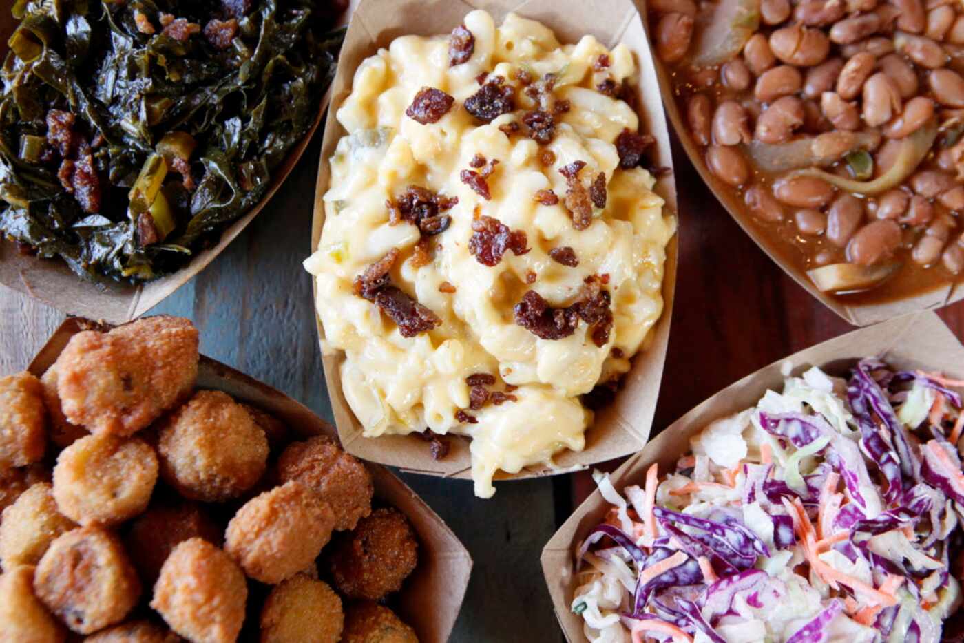 A collection of five sides including collard greens, mac and cheese, pinto beans, fried okra...