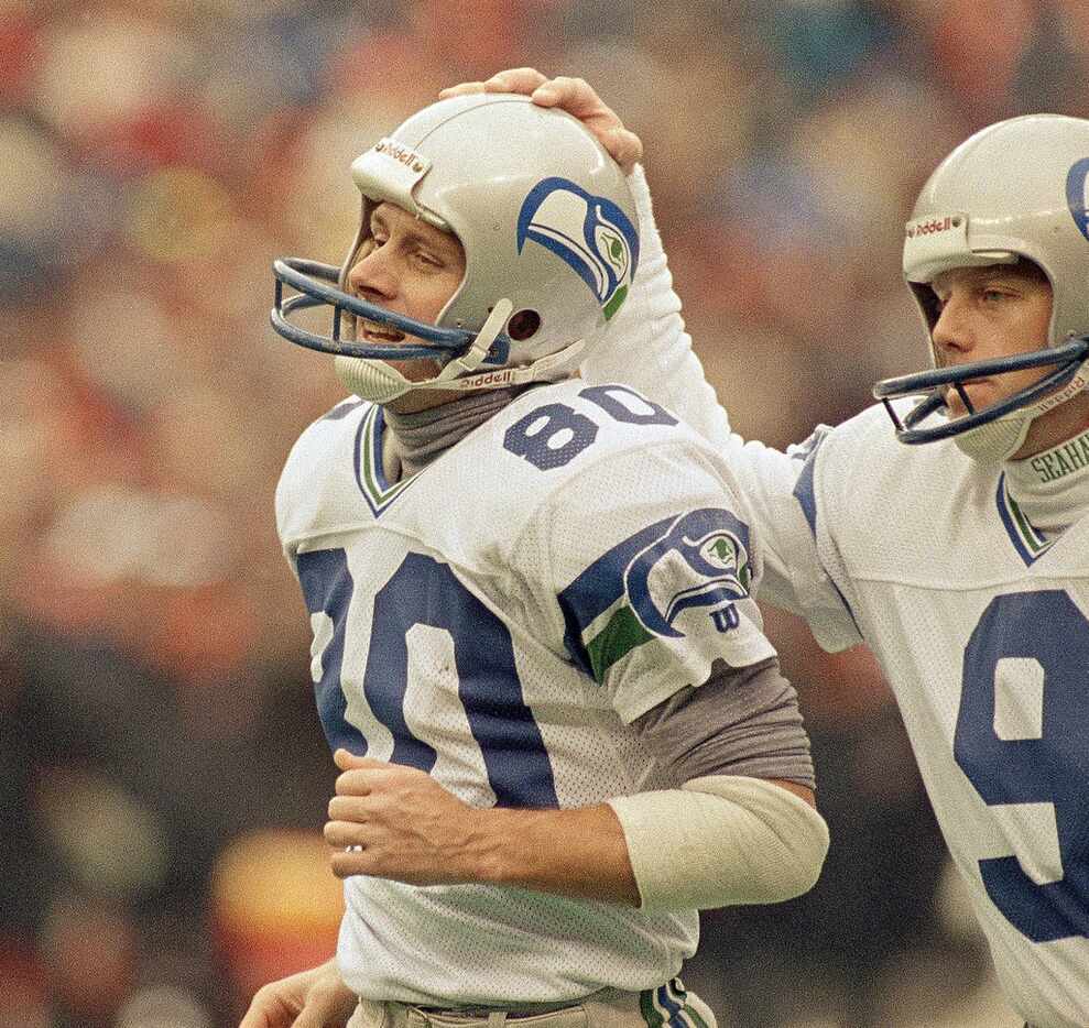 Seattle Seahawks receiver Steve Largent gets a pat on the helmet from teammate Norm Johnson...