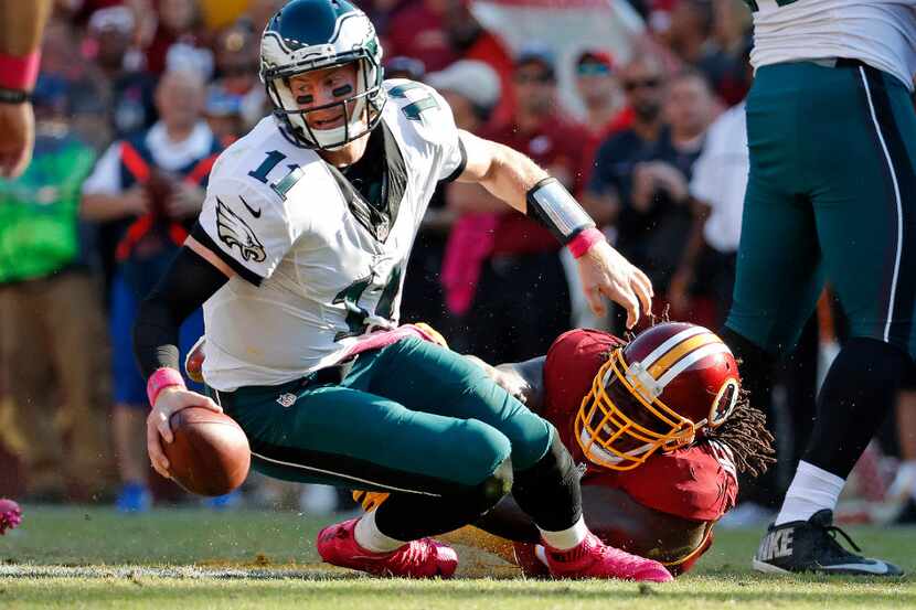 Philadelphia Eagles quarterback Carson Wentz, left, is sacked by Washington Redskins...