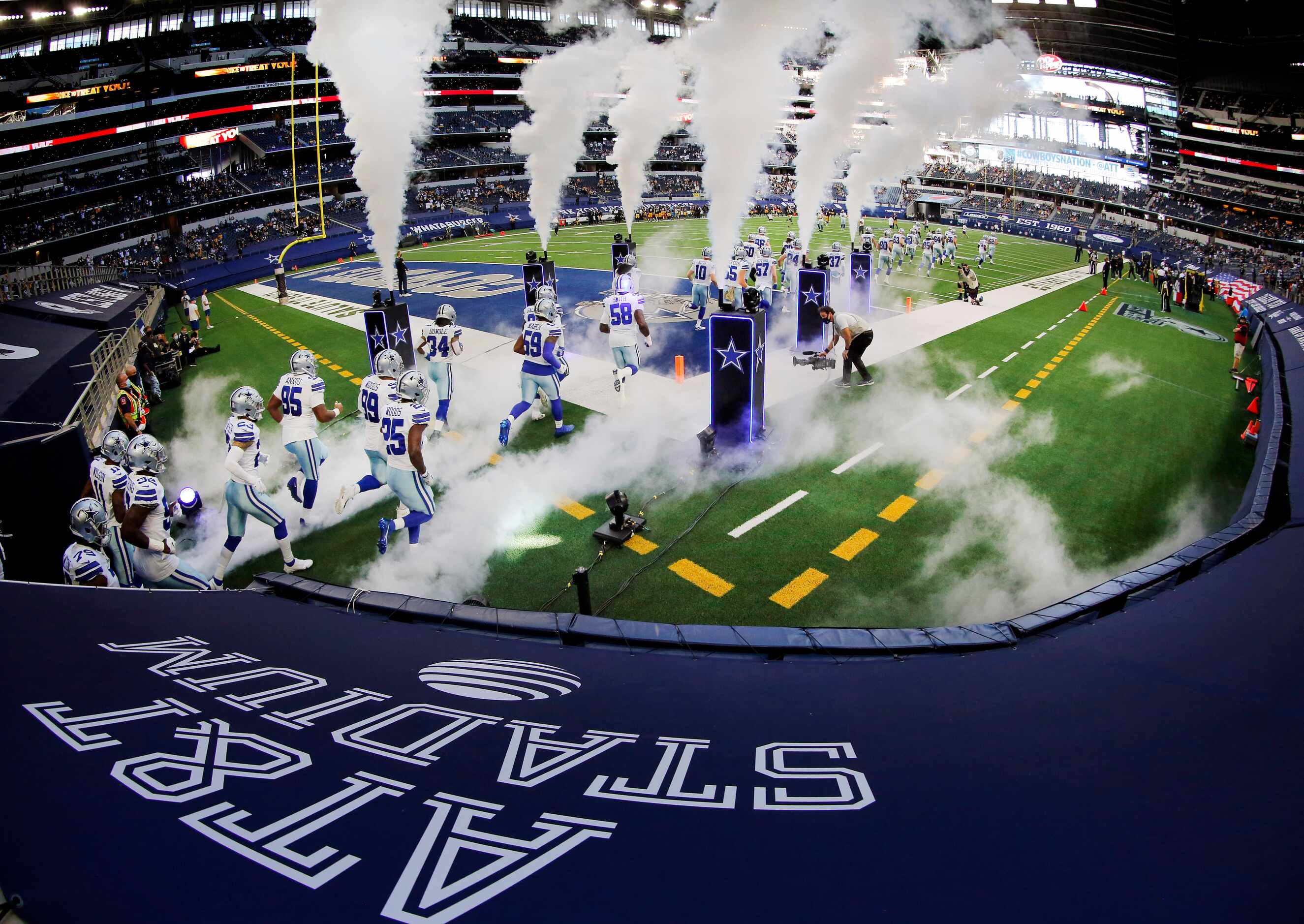 Under a veil of smoke the Dallas Cowboys football team takes the field to face the...
