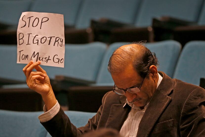 Plano resident Hasan Waqar holds up a sign while Mayor Harry LaRosiliere speaks during a...