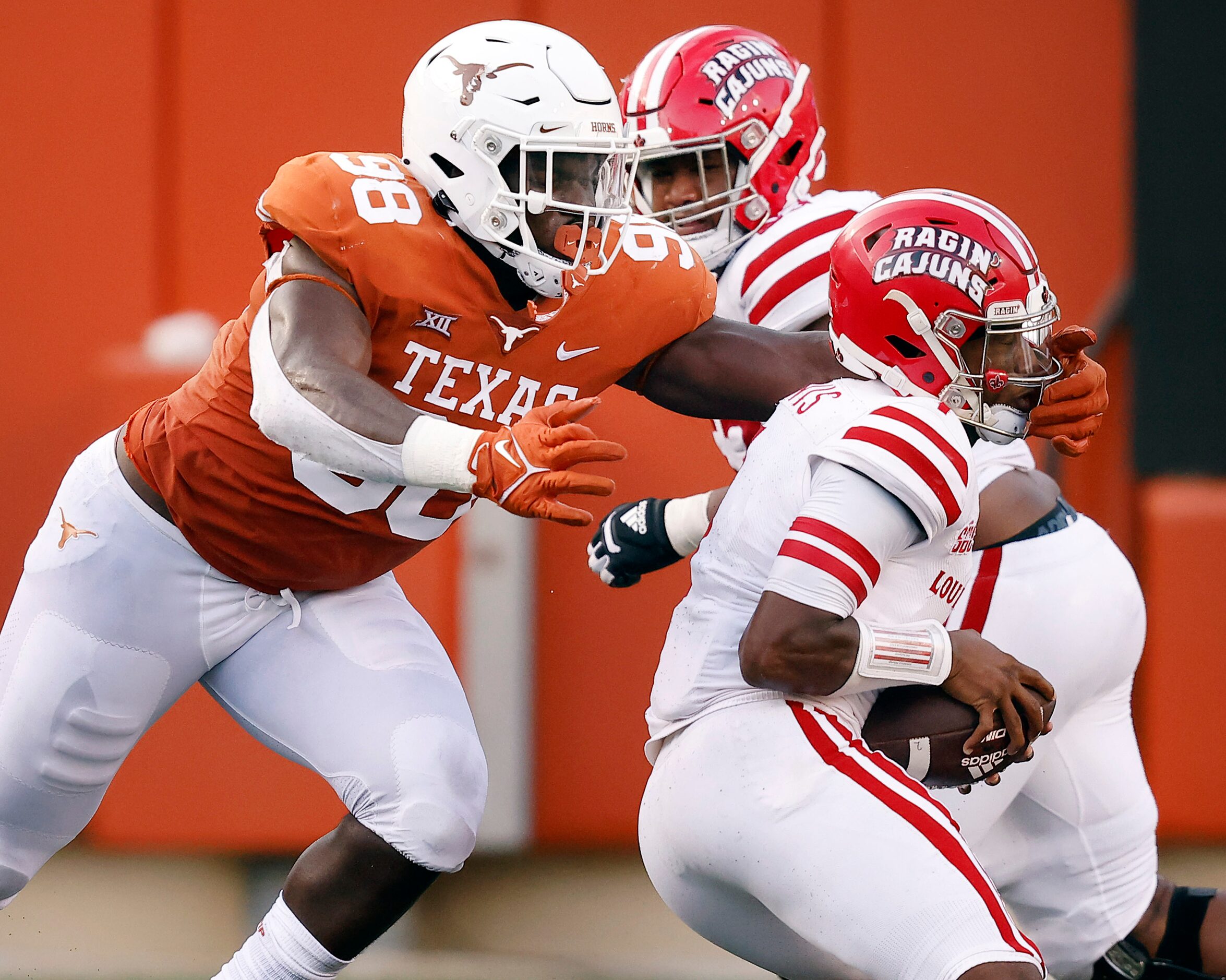 Texas Longhorns defensive lineman Moro Ojomo (98) reaches for Louisiana-Lafayette Ragin...