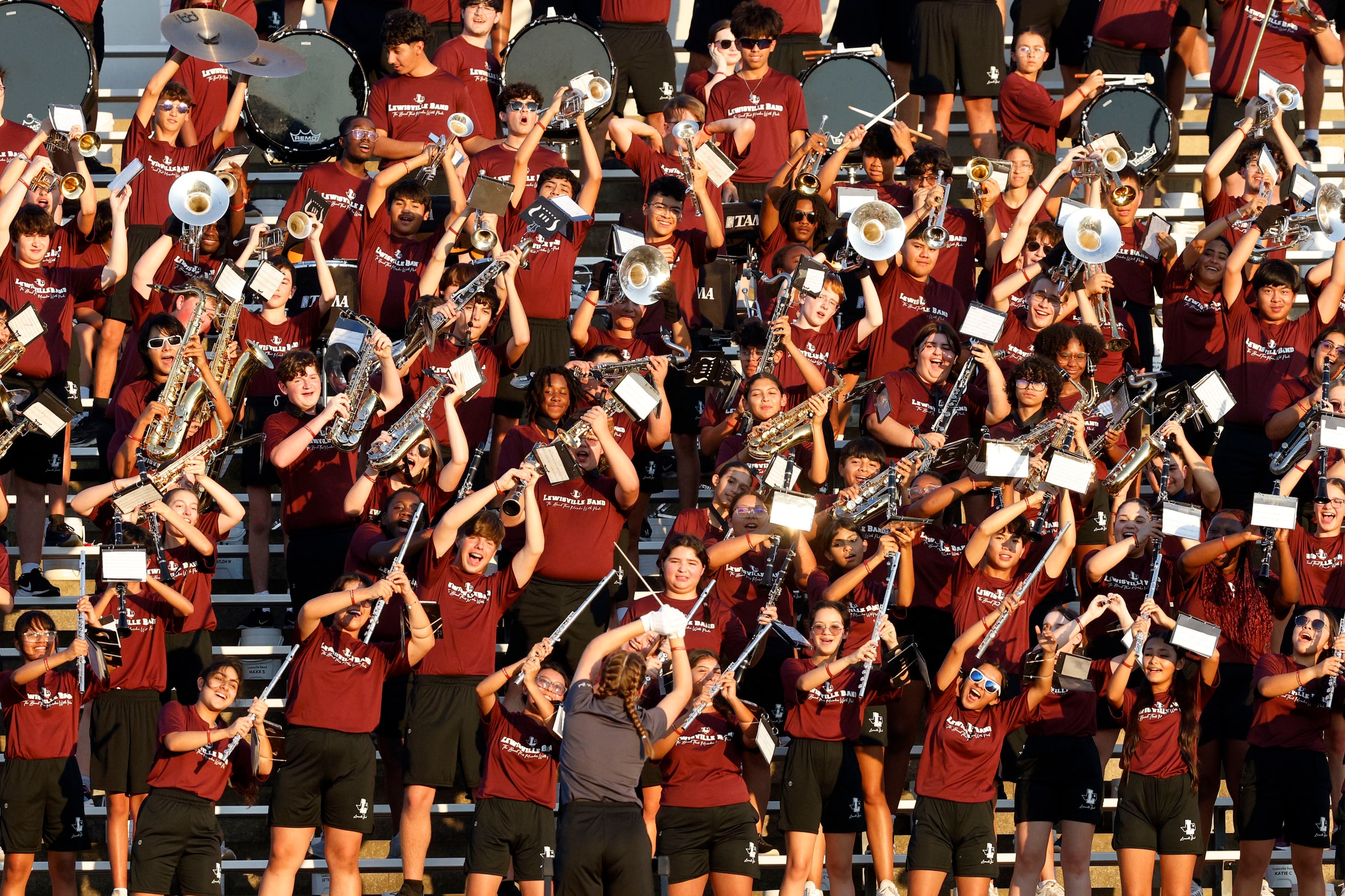 Lewisville marching band members perform during the first half of a high school football...