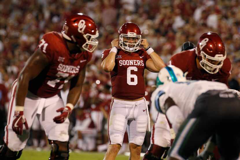 Oklahoma quarterback Baker Mayfield (6) snaps on his helmet during an NCAA college football...