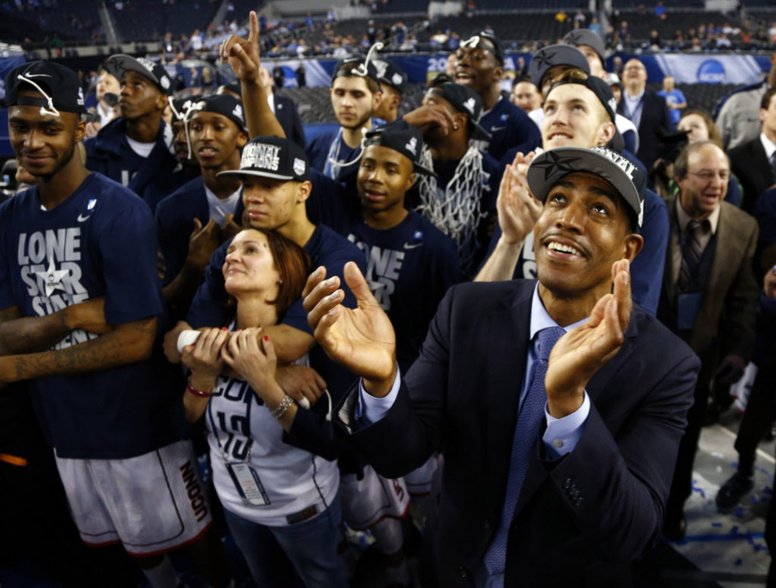 Connecticut Huskies head coach Kevin Ollie and teammates watch highlights on the big screen...