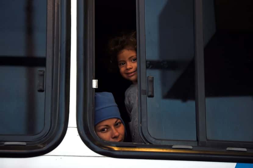 Central American migrants moving in a caravan towards the United States look out from a bus...