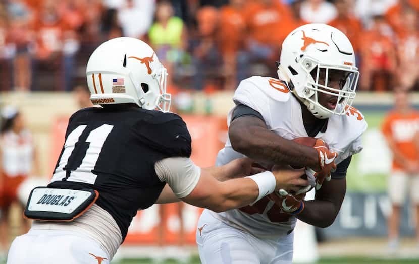 Sam Ehlinger (11) hands the ball off to Toneil Carter (30) during Texas' Orange-White spring...