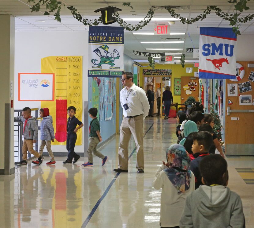 Teacher Assistant Adrian Rivera watches as students make their way through the hallways at...