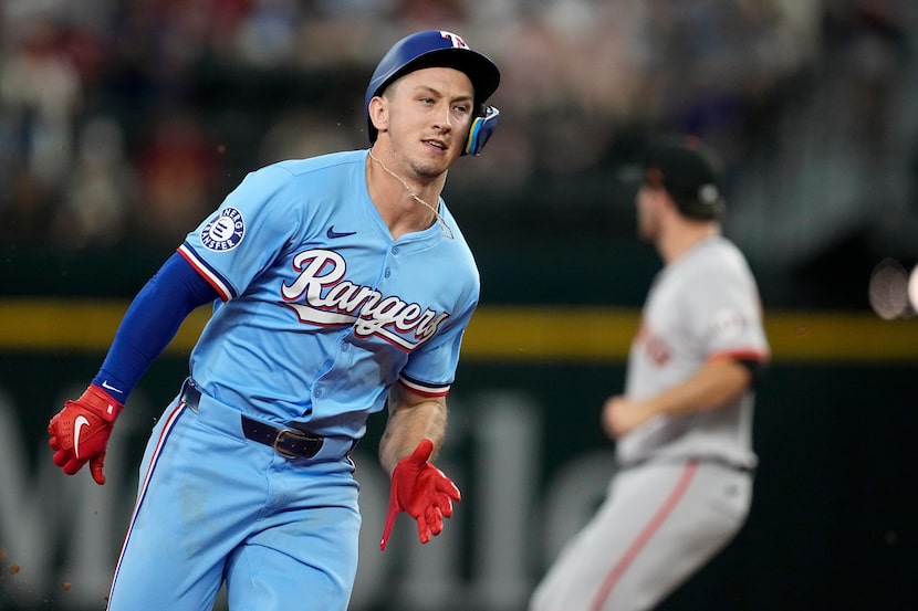 Texas Rangers' Wyatt Langford, left, sprints around second base after hitting a triple...