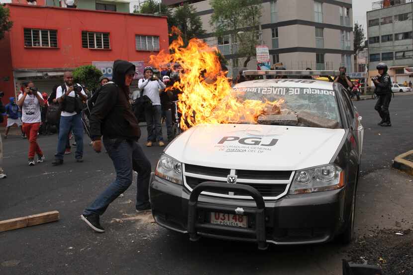 Protesters burn a police vehicle as they march near the airport in Mexico City. Protesters...