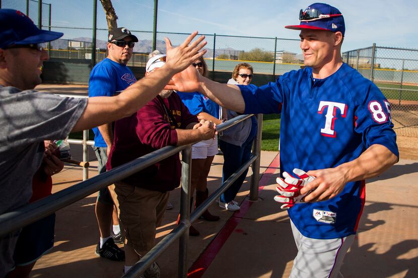 Texas Rangers outfielder Scott Heineman high fives fan Rob Friedman before taking the field...