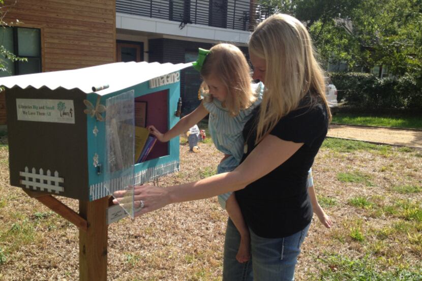 Kimberly Vowell (right) and daughter Reagan, 3, look over the books in their Little Free...