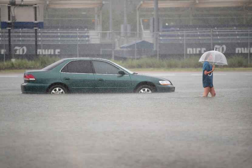 Mari Zertuche walks through a flooded parking lot on the campus of Rice University after it...