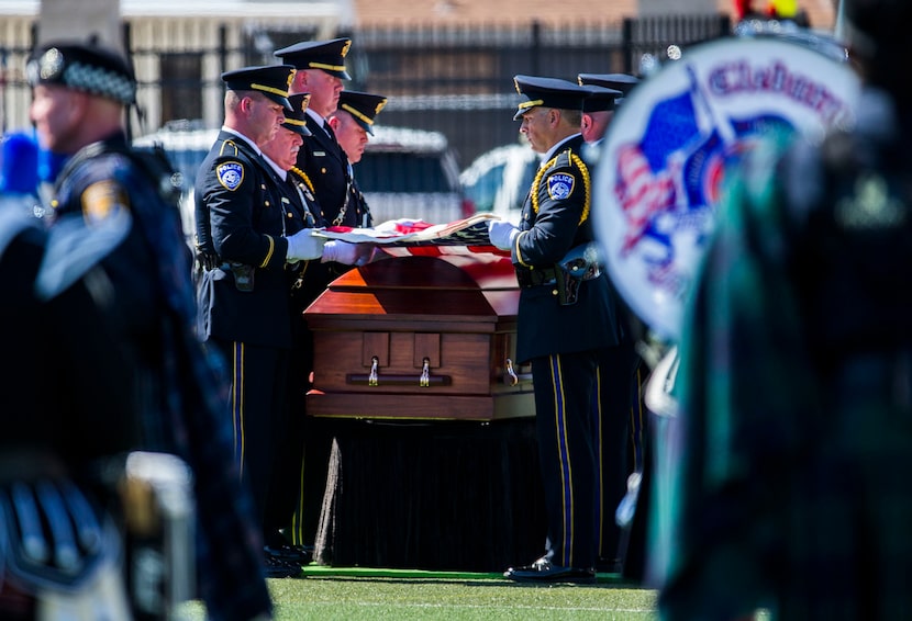  Officers fold an American flag over a casket containing the remains of Euless police...