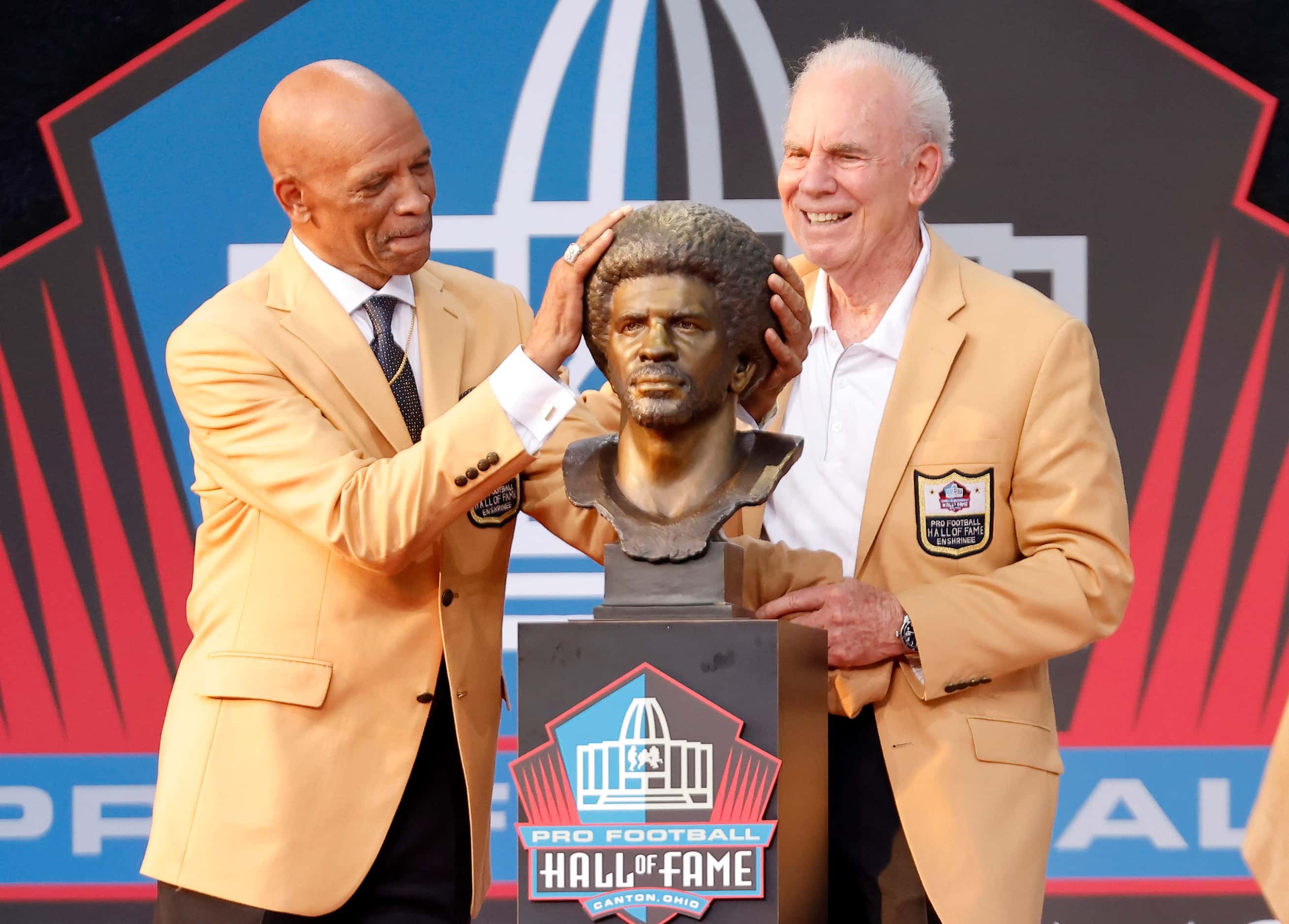 Pro Football Hall of Fame inductee Drew Pearson of the Dallas Cowboys (left) rubs his bronze...