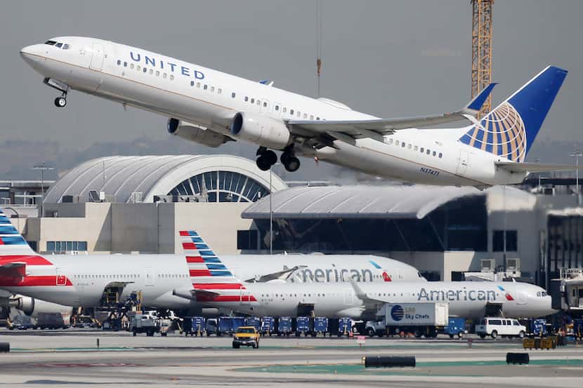 A United Airlines plane takes off above American Airlines planes on the tarmac at Los...