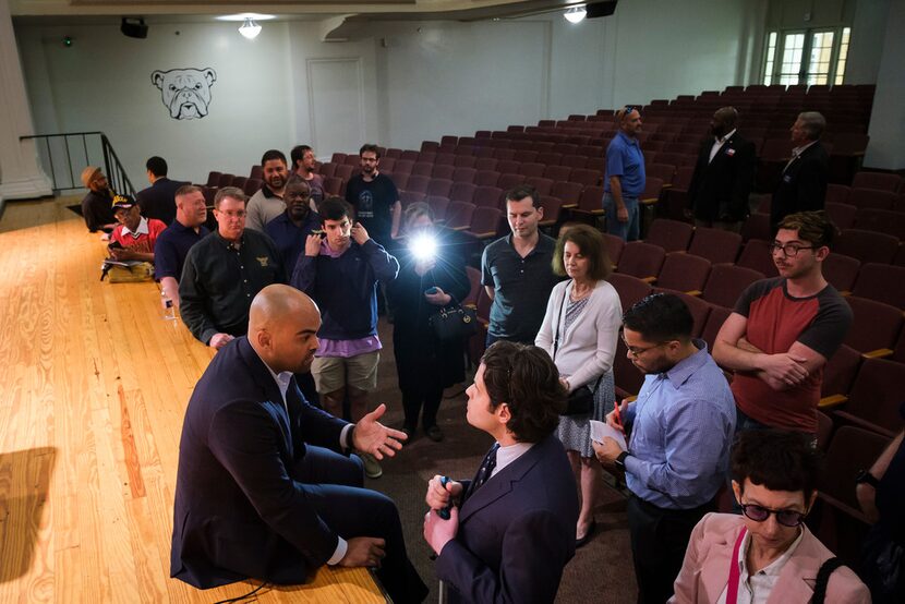 Congressman Colin Allred sits on the edge of the stage and takes questions from the audience...