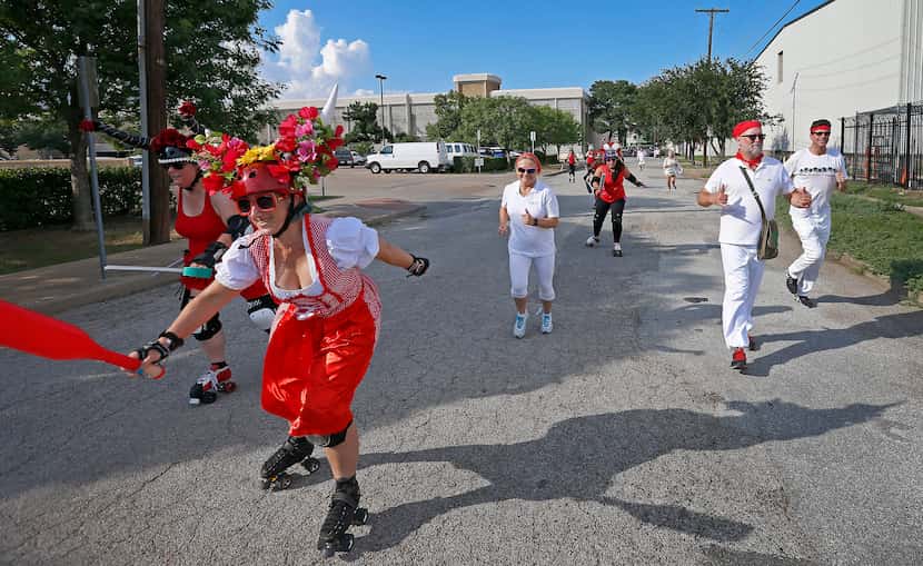 Members of the Dallas Derby Devils roller-skated past runners on McKee Street during the...