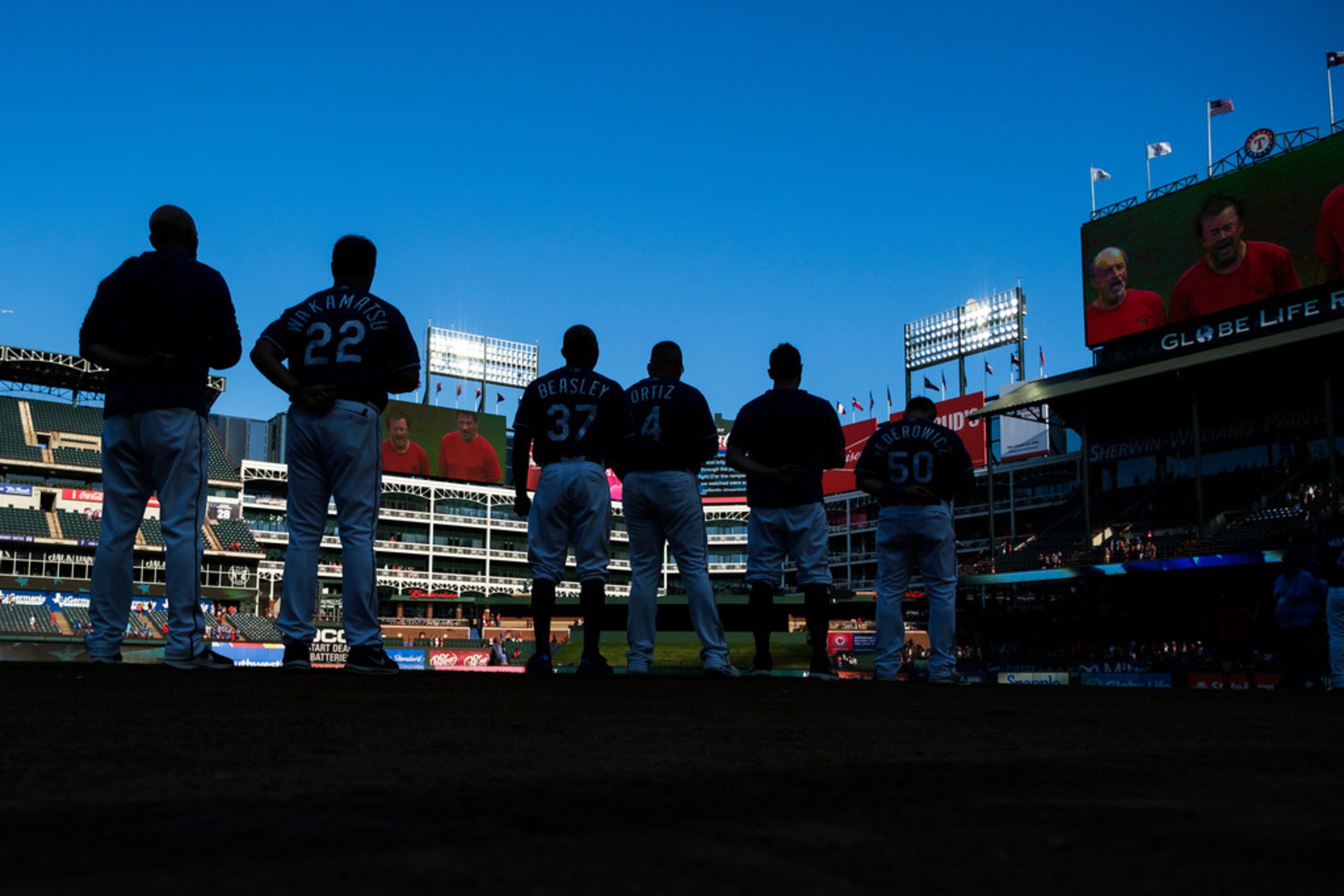 Texas Rangers players and coaches line up for the national anthem before a game against the...