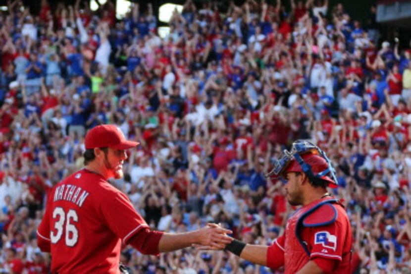 Texas relief pitcher Joe Nathan and catcher AJ Pierzynski shake hands after the final out of...