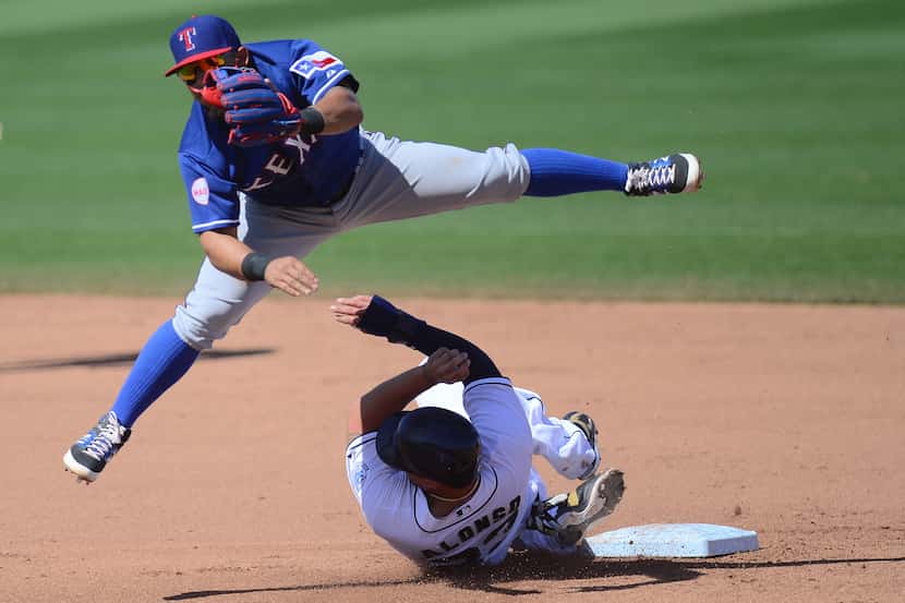 Rangers second baseman Rougned Odor (12) throws to first base after forcing out and leaping...