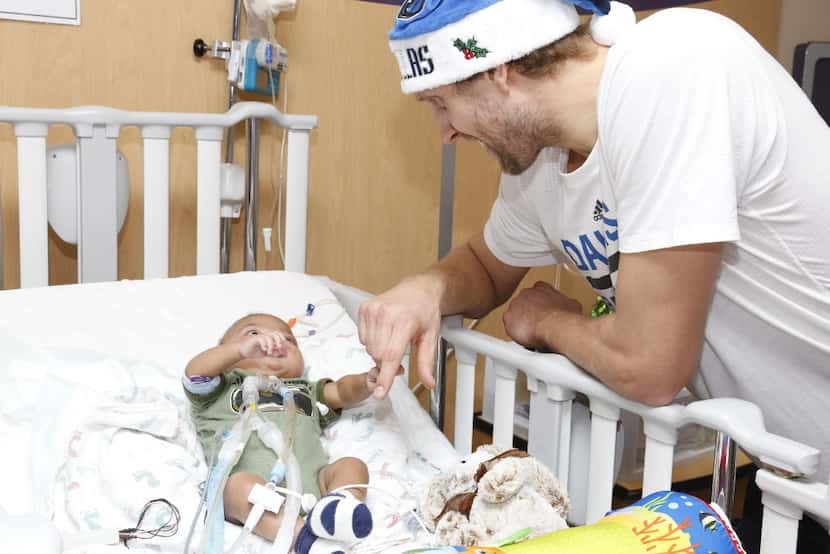 Ryan, 8 months old, grabs Dirk Nowitzki's finger at Children's Medical Center. "He's got a...