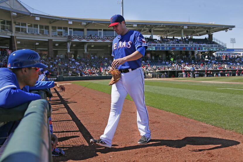 Texas starting pitcher Colby Lewis heads to the dugout after being pulled from the game in...