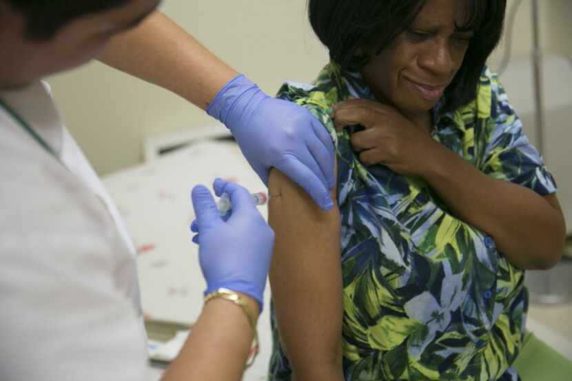 A patient receives a flu vaccine at a Community Clinic Inc. health center in Silver Spring,...