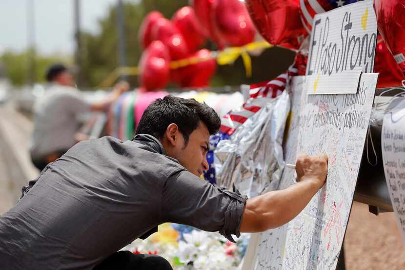 Arturo Roacho of El Paso writes a note on a poster as he visits a makeshift memorial for...