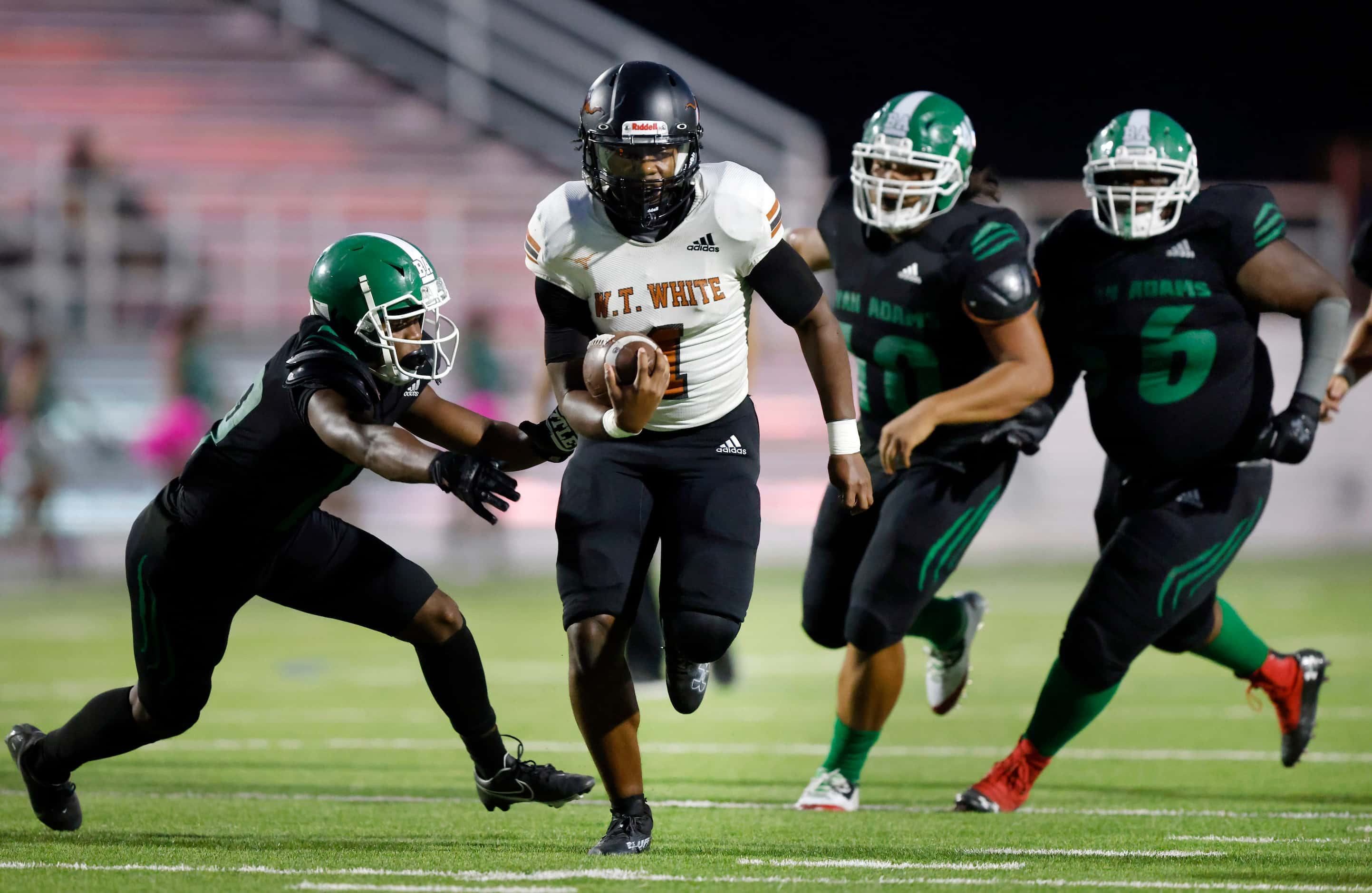 W.T. White quarterback Jaydyn Sisk (1) carries the ball as he’s pursued by the Bryan Adams...