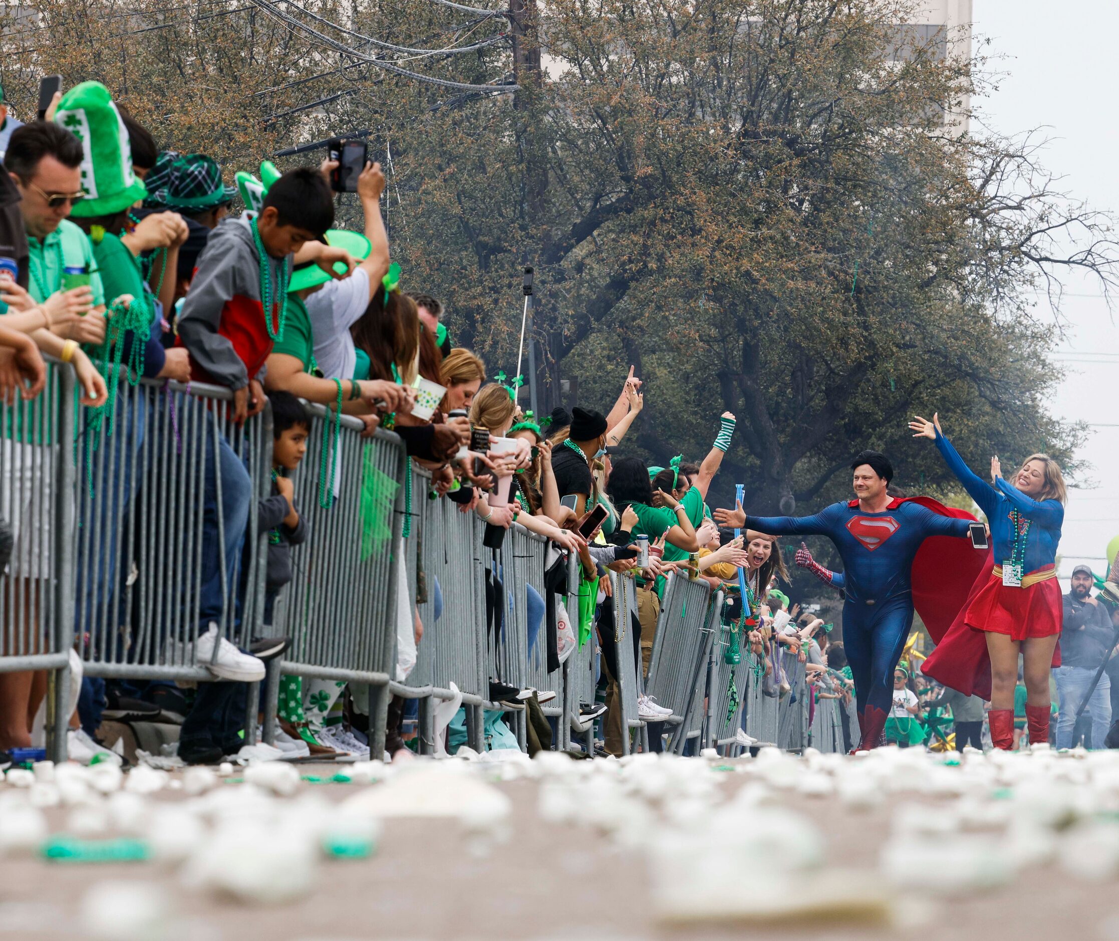 As smushed marshmallow remain along the parade route, DC’s Superman and Supergirl high-fives...