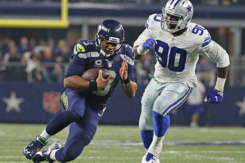 Seattle Seahawks quarterback Russell Wilson (3) scrambles past Dallas Cowboys defensive end...