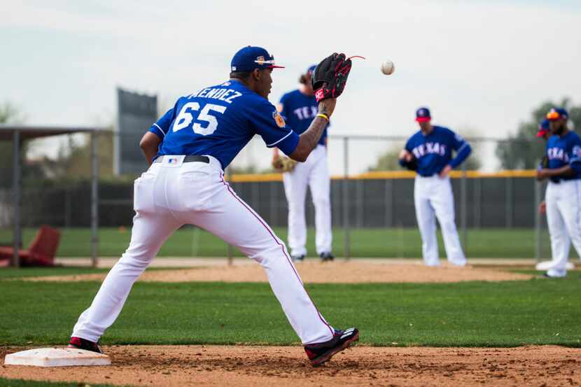 Texas Rangers relief pitcher Yohander Mendez (65) catches a throw to first base during a...