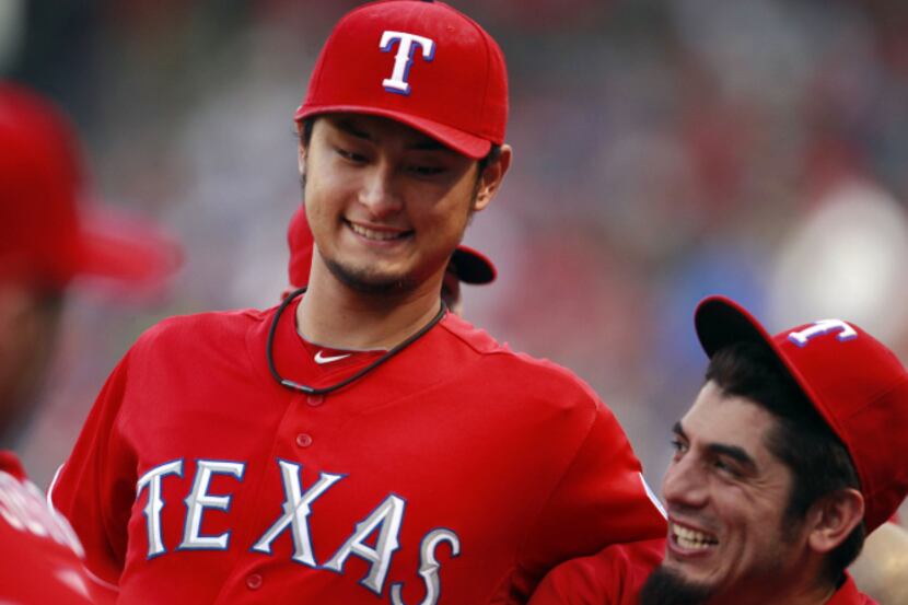 Texas Rangers starting pitcher Yu Darvish (center) jokes with players in the dugout during...