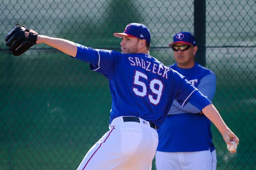 Texas Rangers pitcher Connor Sadzeck throws a bullpen session as pitching coach Julio Rangel...
