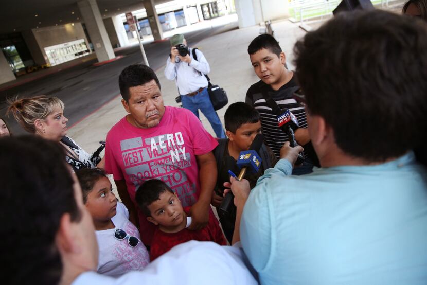 Luis Banda (far right), 12, an evacuee from Dickinson, Texas, speaks to the media alongside...
