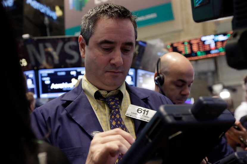 FILE - In this Friday, March 28, 2014, file photo, Trader Daniel Trimble, left, works on the...