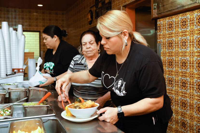 Yolanda Bravo serves a dish next to Artemia Adame and Monica Adame at a Chuy's Mexican...