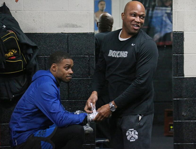 Trainer Derrick James, right, tapes up the wrists of boxer Errol Spence Jr. before their...