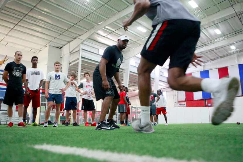 Defensive back football trainer Clay Mack observes the foot technique of young players...