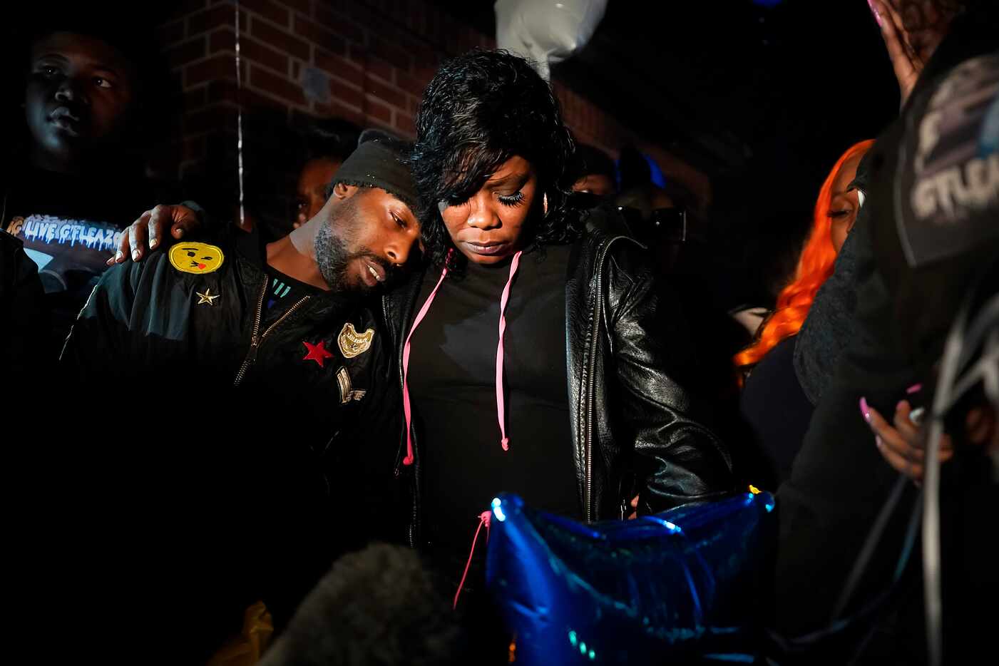 Monique Mitchell (center) is consoled during a vigil for her son Marc "Flea" Strickland, an...
