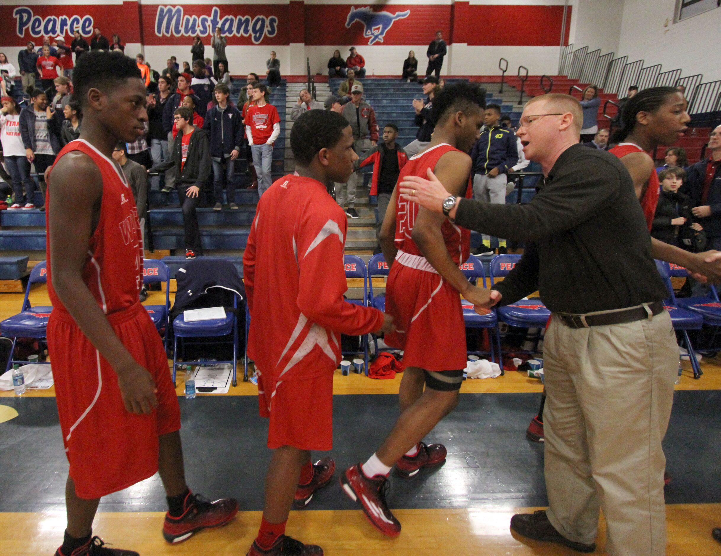 Frisco Centennial head coach Mike Scarbrough congratulates members of the Woodrow Wilson...