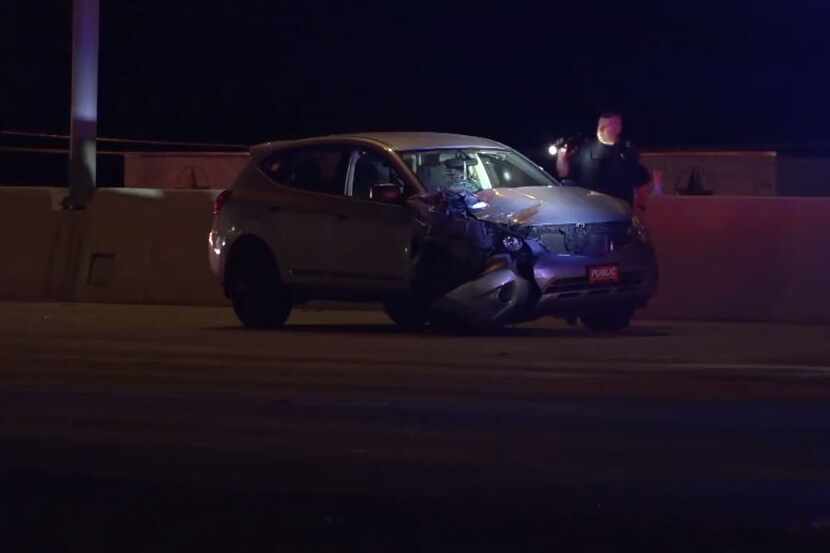 A police officer looks over a damaged SUV after it struck a motorcycle rider trying to get...