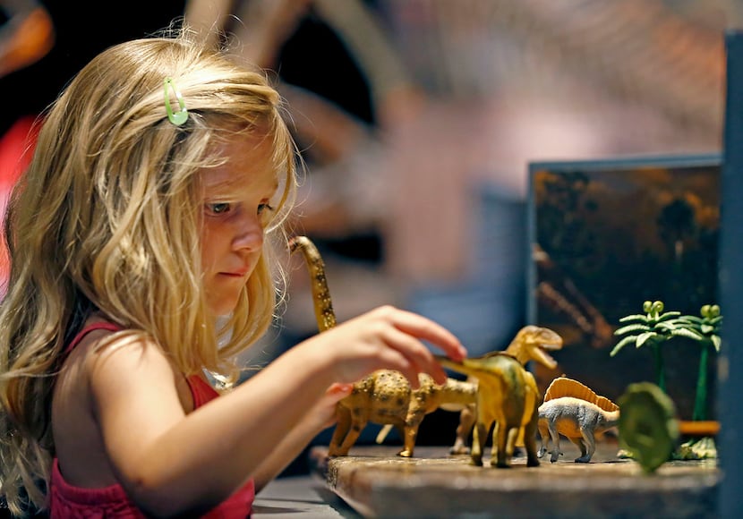 Kaydence Frymyer, 4, of Denton plays with dinosaur toys during a media preview of new...