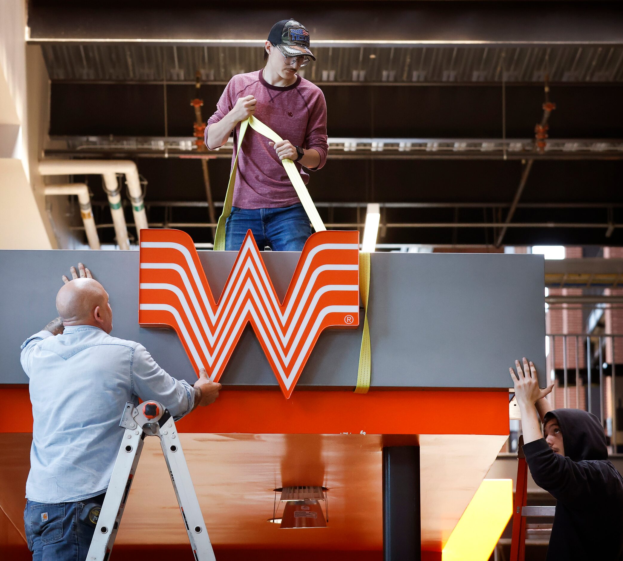 Workers install the W at the Whataburger restaurant at Globe Life Field in Arlington as the...