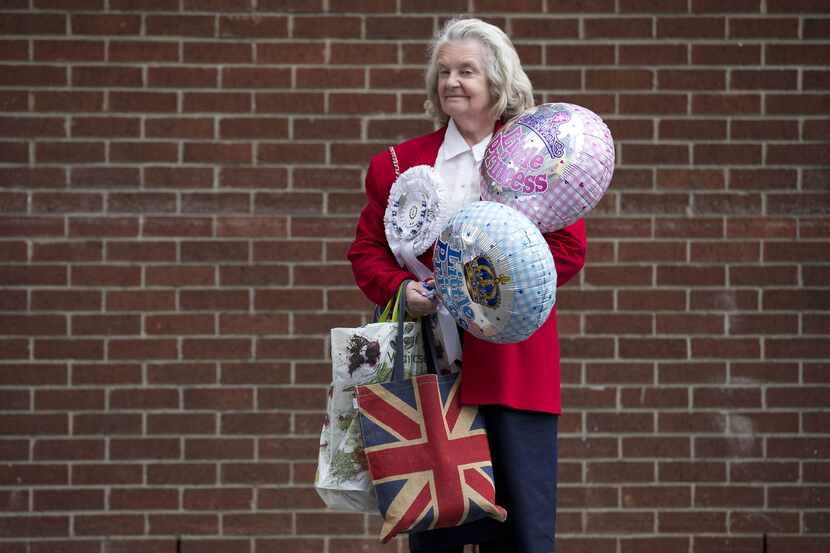 A royal fan holding little prince and little princess balloons stands outside St. Mary's...