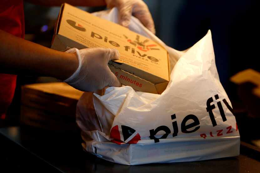 Victor Enriquez puts pizza into a bag at Pie Five in Lewisville, Texas on Friday, Dec. 30,...