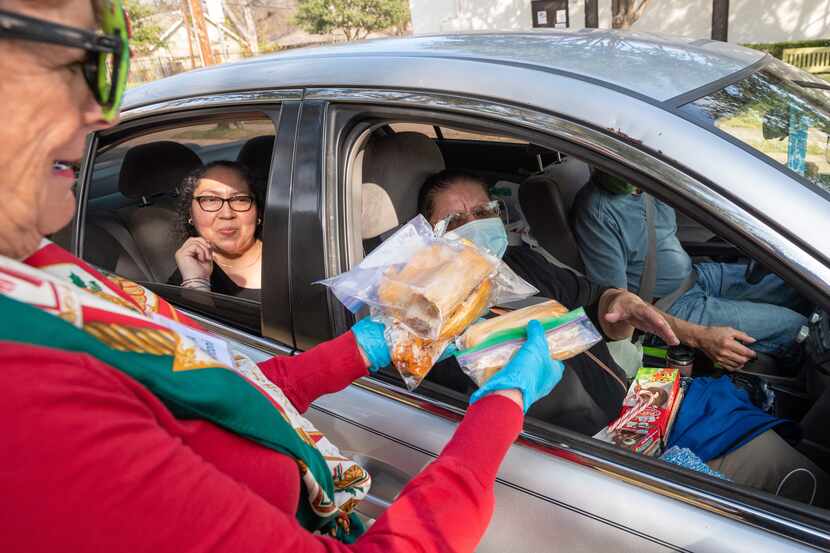 Yolanda Aviles, left, and Consuelo Olivo, right, receive bags of tamales from volunteer...