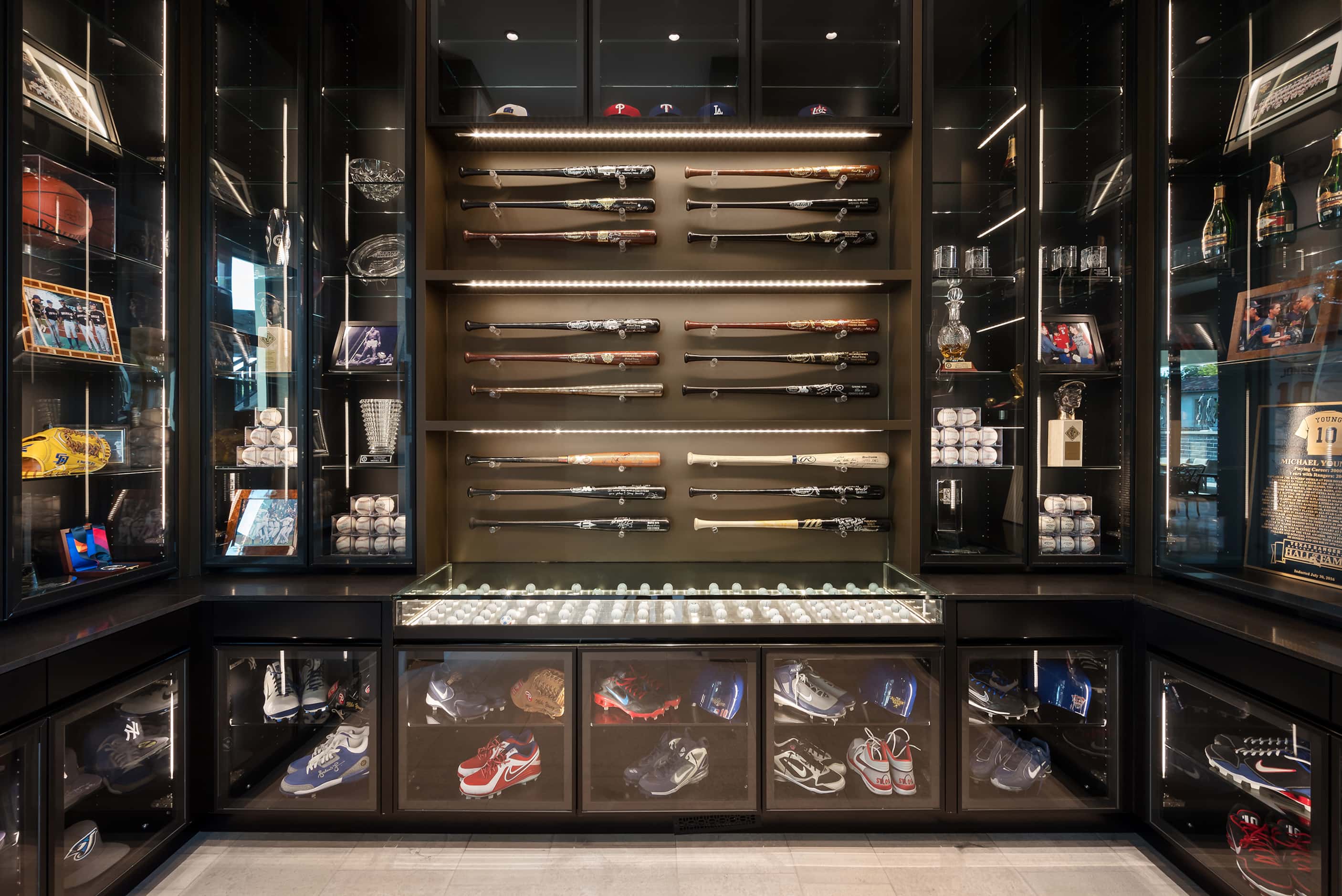 Display cabinets show off a collection of sports memorabilia, including baseballs, bats and...