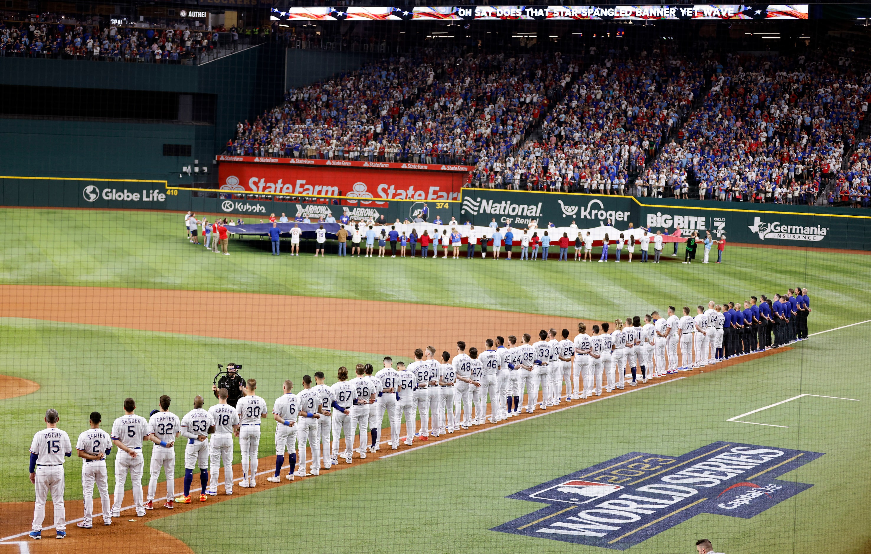 The Texas Rangers players and coaching staff line up along the baseline for the national...